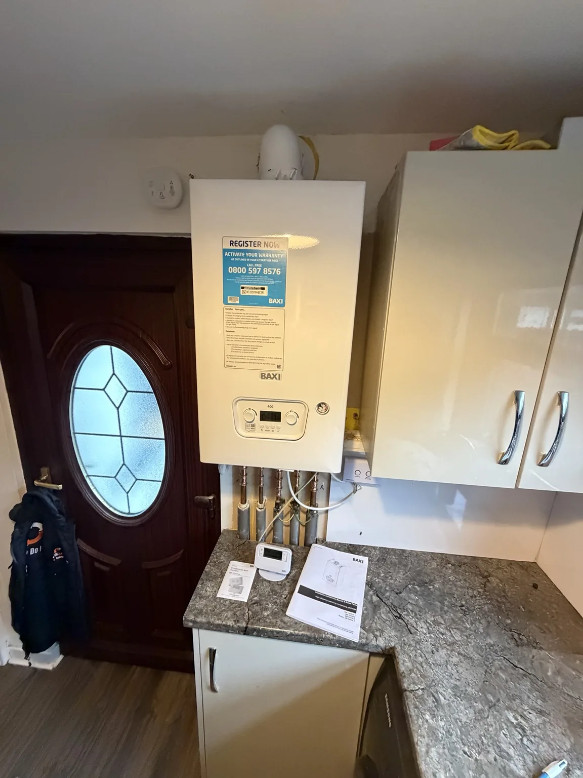 Newly installed Baxi 400 combination boiler above kitchen worktop with installation documents