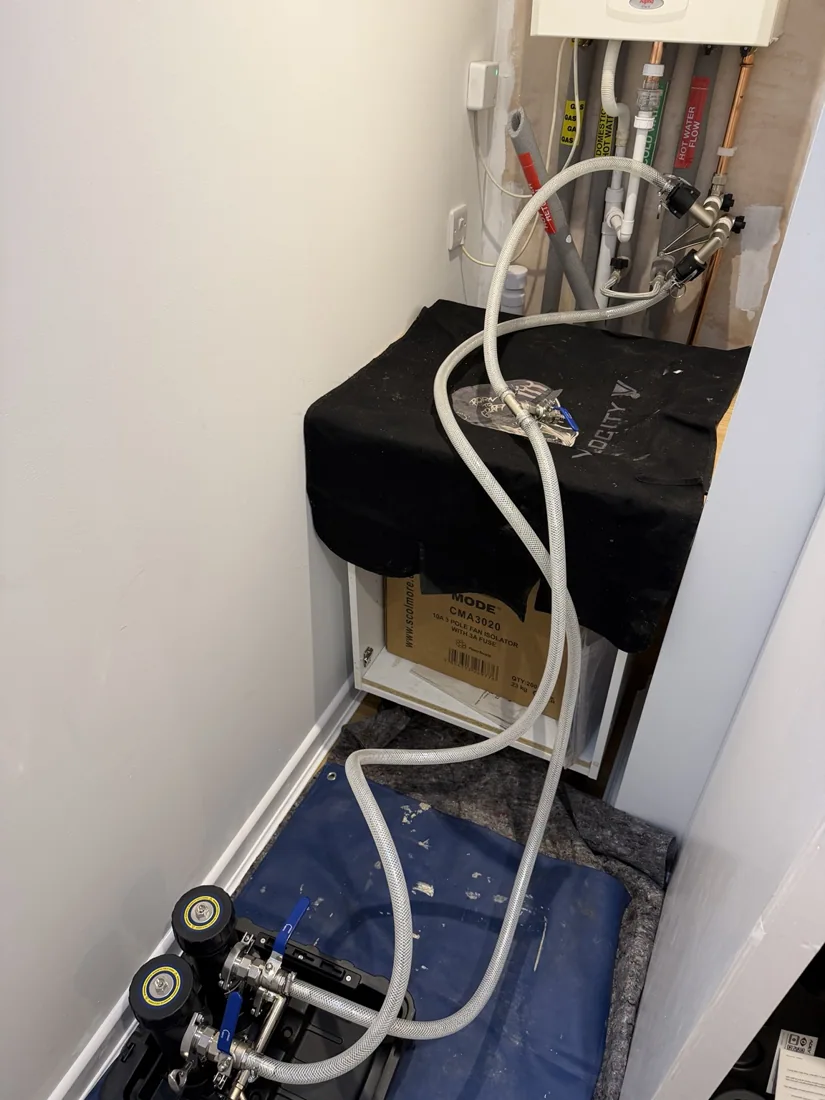 MagnaCleanse hoses connected to central heating pipework with kitchen worktop protected